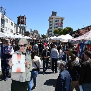 A bustling outdoor market with people enjoying a sunny day.