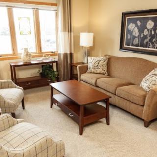 A cozy living room with a sofa, armchairs, and a wooden coffee table.