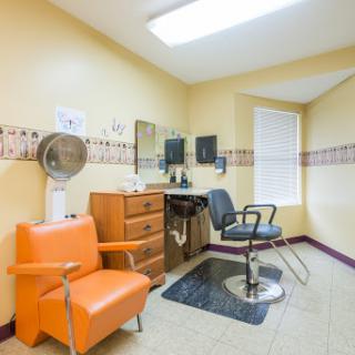 A cozy barber salon featuring an orange chair and a styling station.
