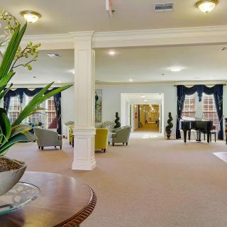 Spacious living room with elegant decor, featuring a piano and large windows.