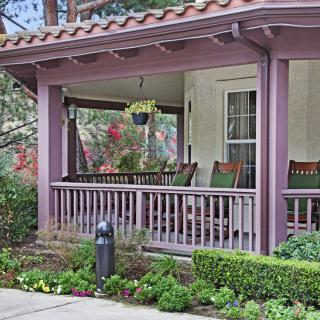 A cozy porch with rocking chairs and hanging plants, surrounded by greenery.