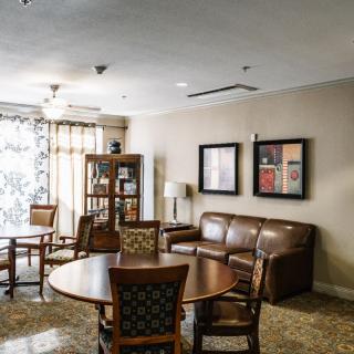 A cozy living room with a round table, chairs, and a leather sofa.