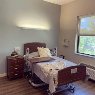 A well-lit hospital room featuring a patient bed and a nightstand.