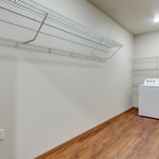 A spacious laundry room with a washing machine and wire shelves.