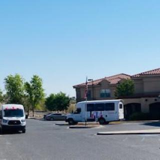A sunny day in a parking lot with parked vans and a nearby building.