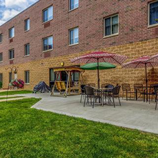 Outdoor patio area with tables and colorful umbrellas next to a brick building.