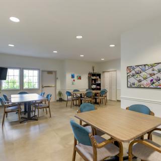 A spacious and well-lit meeting room featuring tables, chairs, and decorative artwork on the wall.