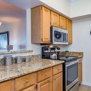 A modern kitchen featuring wood cabinets, granite countertops, and stainless steel appliances.