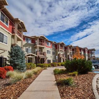A modern apartment complex with a landscaped walkway under a cloudy sky.
