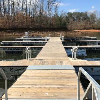 A wooden dock stretches over calm lake waters with boats moored on either side.