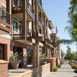 A modern residential street with multi-story buildings featuring balconies and potted plants.