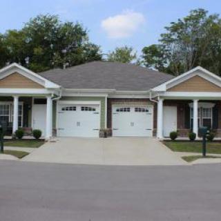 A duplex with two garages and driveways in a residential neighborhood.