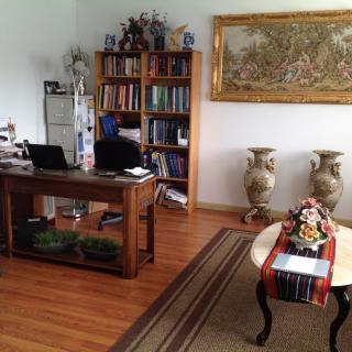 A cozy office space with a wooden desk, bookshelf, and decorative elements.