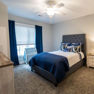 A modern bedroom with a neatly arranged bed and blue accents.