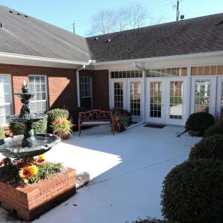 A serene courtyard featuring a fountain and outdoor seating surrounded by a brick building.