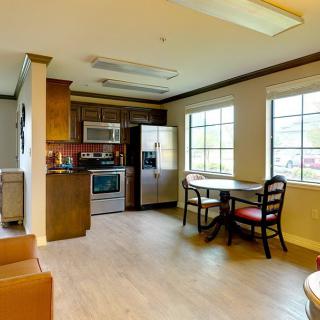 A cozy kitchen and dining area with modern appliances and a small table by the windows.