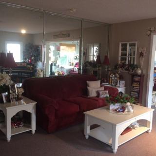 A cozy living room with a red sofa, white coffee and side tables, mirrors on the wall, and various decorations.