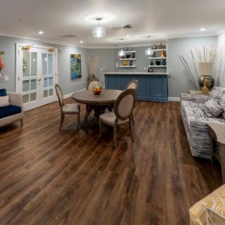A modern living room with wood flooring, featuring a round table and comfortable seating.