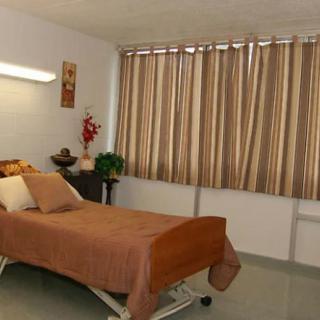 A well-maintained hospital room featuring a single bed with brown bedding and curtains.