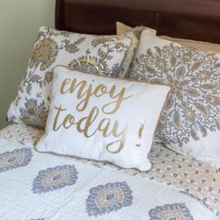 A cozy bedroom setting featuring a decorative pillow with an inspiring message.