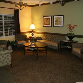 A cozy living room featuring sofas, a lamp, a coffee table, and wall art.