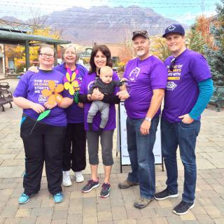 A group of people wearing purple shirts posing together outdoors.