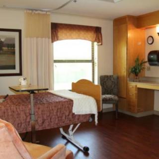 A well-organized hospital room with a bed, chairs, and medical equipment.