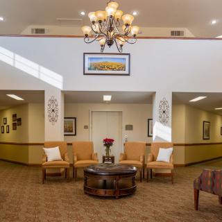 A well-lit lobby area featuring comfortable seating, a chandelier, and decorative artwork.