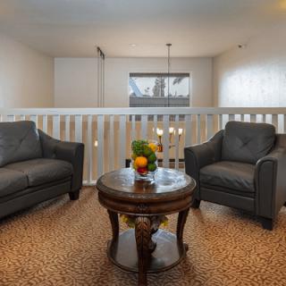 A cozy living room area with two armchairs and a round wooden table, featuring contemporary decor and ambient lighting.
