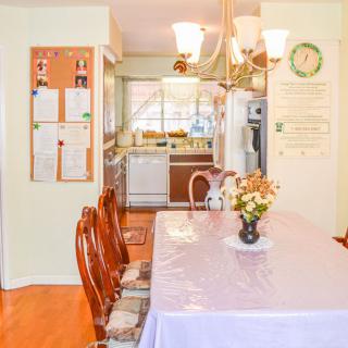 A cozy dining room with a table set for a meal, leading into the kitchen area.