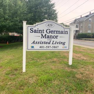 A sign for Saint Germain Manor Assisted Living located outdoors near a building.