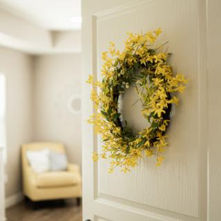 A vibrant yellow flower wreath adorns a door, adding a touch of warmth to the home interior.