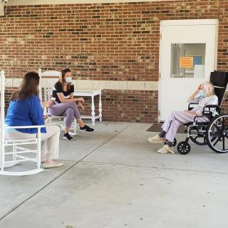 A group of people sitting outside a nursing home, engaging in conversation.