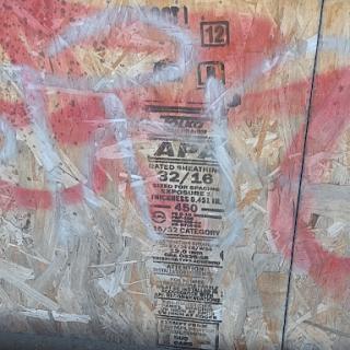 A weathered urban wall featuring graffiti and a faded poster.
