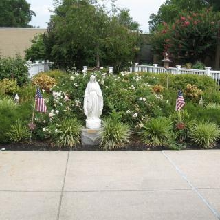A garden featuring a statue surrounded by flowers and small American flags.