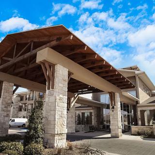 A building entrance with stone pillars and wooden beams under a blue sky.