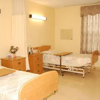 A hospital room with two patient beds and basic furnishings.