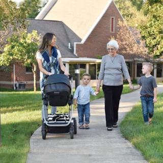A family enjoying a beautiful day outdoors, taking a stroll together with a stroller.