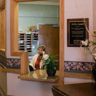 A receptionist at an office, engaging on the phone amidst a well-decorated workspace.