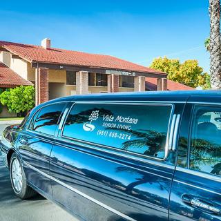 A luxury limousine parked in front of a building on a sunny day.