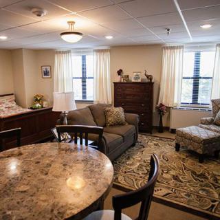 A cozy apartment interior featuring a combined living and sleeping area with a sofa, bed, dining table, and comfortable seating.