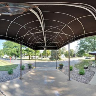 A view of a spacious outdoor canopy structure surrounded by greenery.