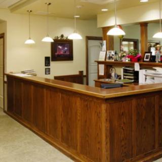 A reception desk in an office setting with wooden furniture and overhead lighting.