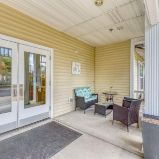 A cozy porch area with a sofa and chairs arranged around a small table near a building entrance.