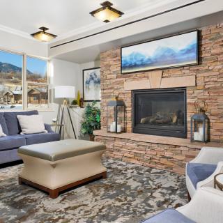 A modern living room featuring a brick fireplace, stylish furniture, and large windows with a scenic view.