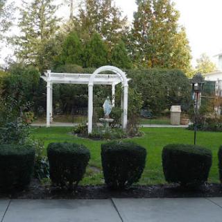 A serene garden featuring a white archway and a central sculpture.