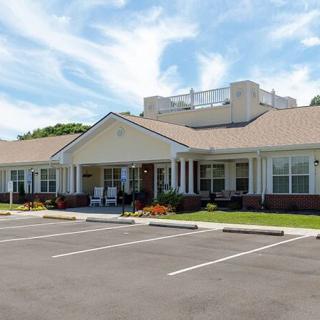 A single-story building with a parking lot in front, set against a cloudy sky.