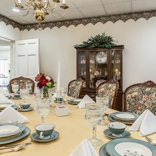 An elegantly set dining room table with fine china and a floral centerpiece.