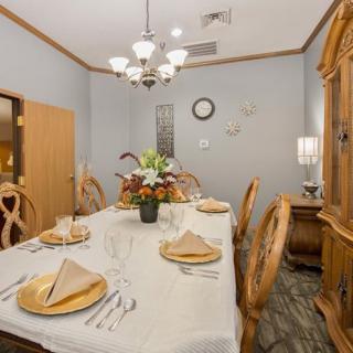 A neatly arranged dining room with a long table, chairs, and elegant decorations.