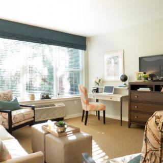 A bright and cozy living room with a large window letting in natural light, featuring comfortable seating and stylish decor.